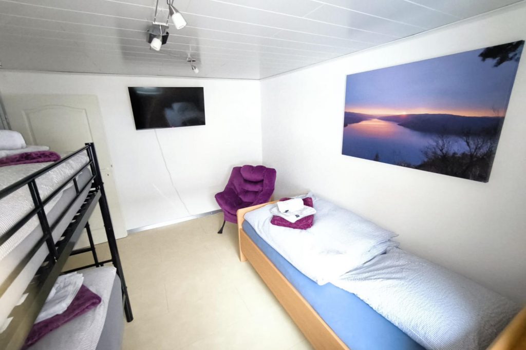 Zweites Schlafzimmer im Ferienhaus CaSa Hürtgenwald mit Etagenbett, Einzelbett und modernem Smart-TV.