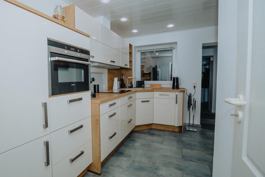 Moderne, voll ausgestattete L-Küche mit hochgebautem Siemens-Backofen und Fenster im Ferienhaus CaSa Hürtgenwald.