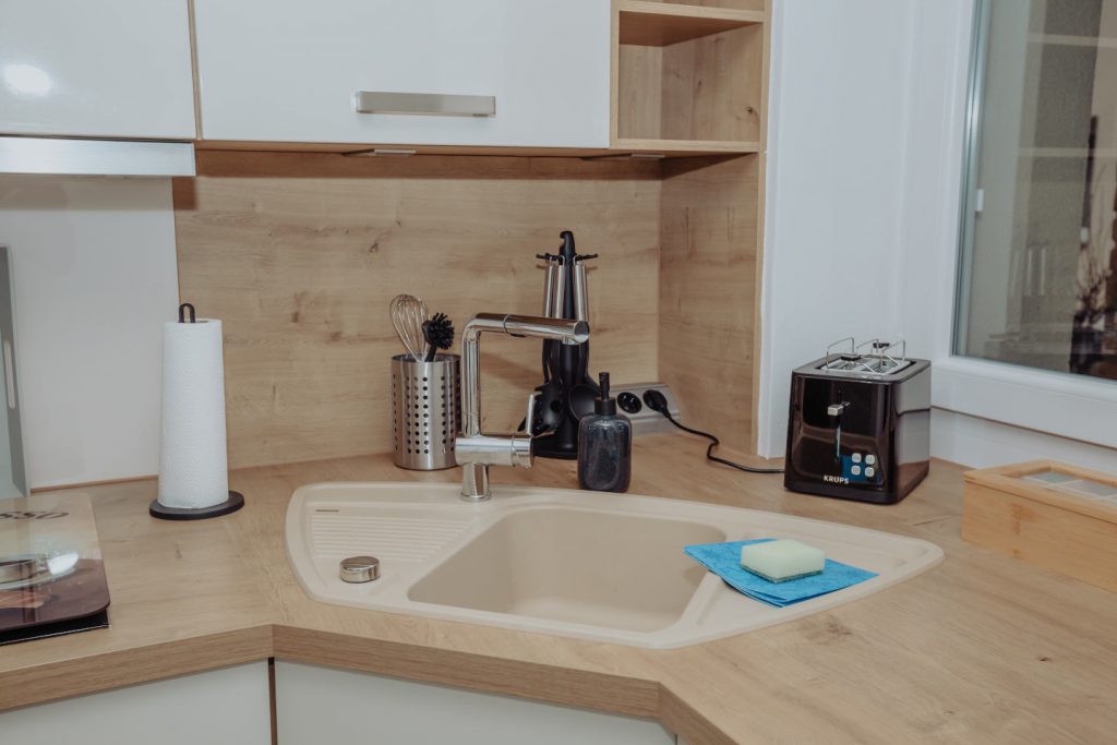 Moderne Eckspüle in der Küche der CaSa Hürtgenwald mit Holzarbeitsplatte, Toaster und Küchenutensilien.