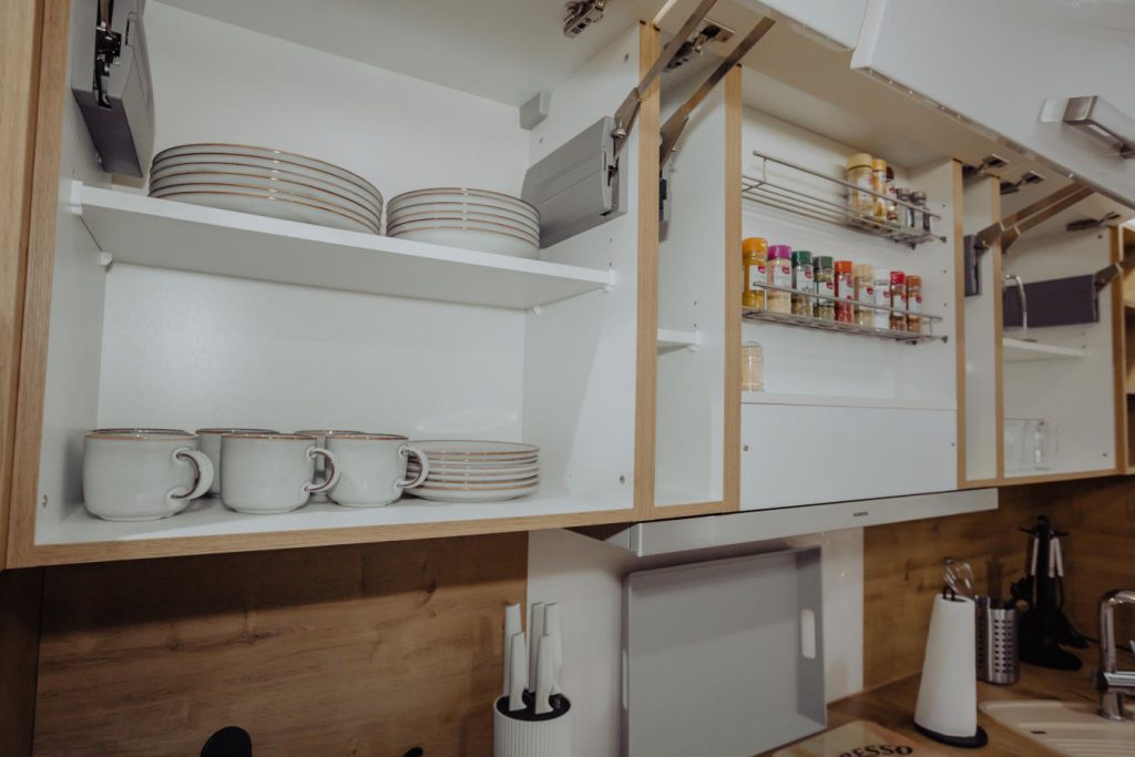 Geöffnete Küchenschränke mit Geschirr und Gewürzregal